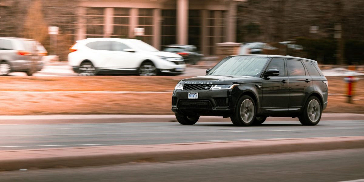 A luxury Range Rover speeding on a city street in Canada, captured with motion blur highlighting its velocity.